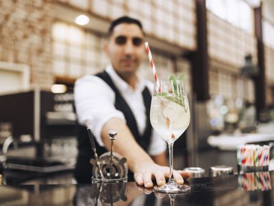 Barkeeper reicht Cocktail an der Bar